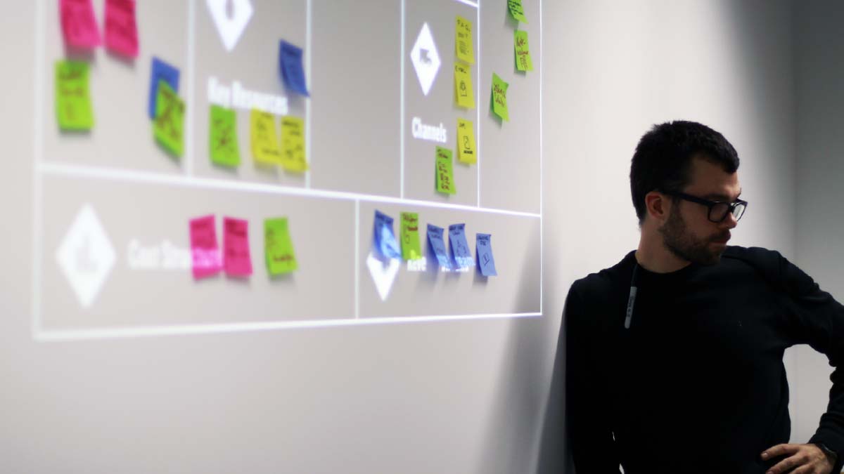 Designer and teacher Hannes Jentsch standing next to a projected business model canvas